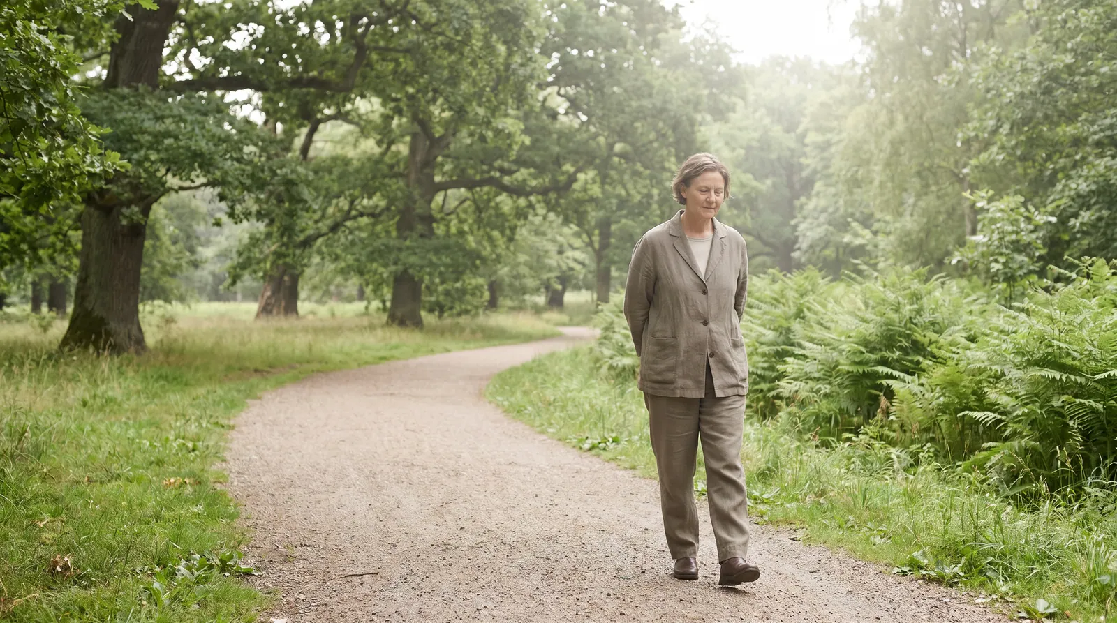 A person walking in a quiet path surrounded by trees in golden hour light
