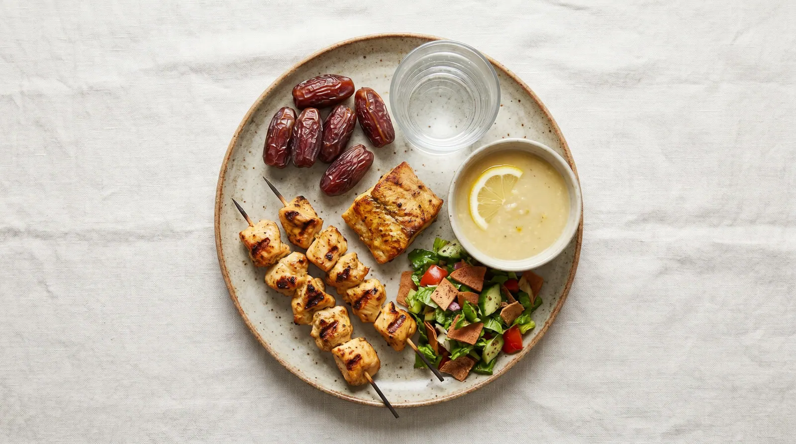 A balanced iftar plate: dates, water, lentil soup, protein, and vegetables